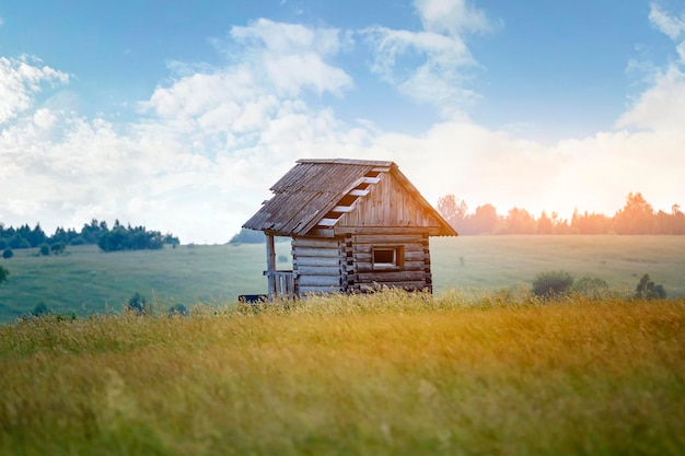 Casa di legno abbandonata in piedi solitaria tra un campo in campagna.