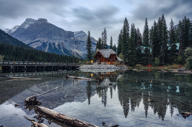 Casa di legno con la montagna rocciosa in abetaia nel lago verde smeraldo