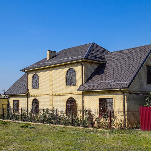 Casa di mattoni gialli e tetto ondulato marrone in metallo Reticoli sulle finestre