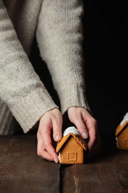 Casa di pan di zenzero di Natale del regalo della mano della donna sulla tavola di legno