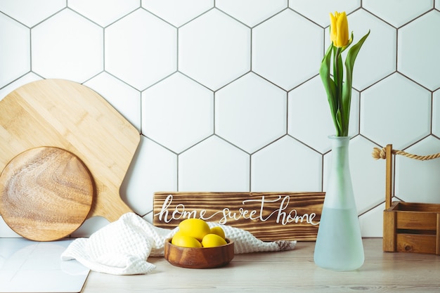 Casa dolce casa segno sulla ciotola di legno del controsoffitto della cucina con le uova di Pasqua e il tulipano giallo in vaso