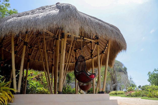 Casa ecologica tradizionale in bambù con sedia sospesa in rattan nel parco.