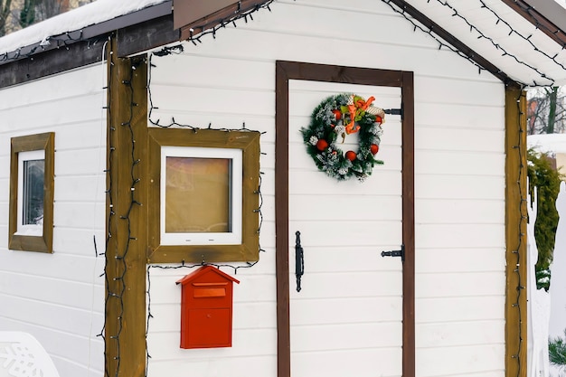 Casa in legno bianco della struttura artificiale di Babbo Natale con cassetta postale rossa per lettere di bambini bambini nel parco cittadino innevato d'inverno. Natale Natale Capodanno concetto di vacanza.