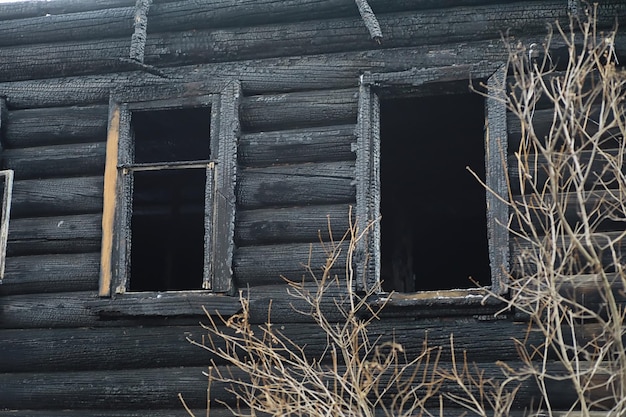 Casa in legno dopo l'incendio. Carboni sui tronchi. Le ceneri della casa dal fuoco. Casetta distrutta bruciata.