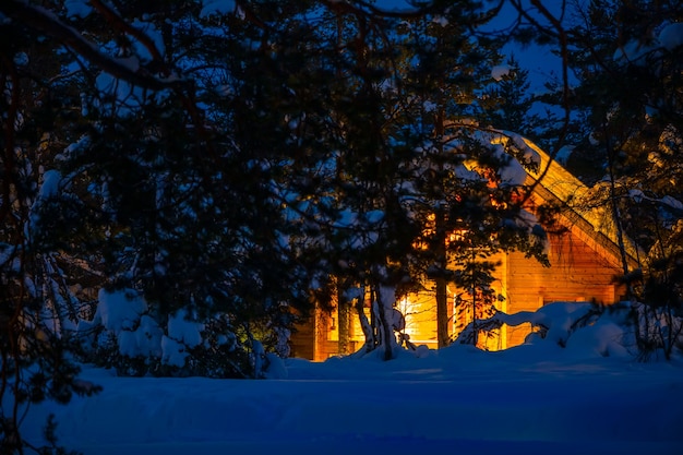 Casa in legno nella foresta invernale di notte. Molta neve