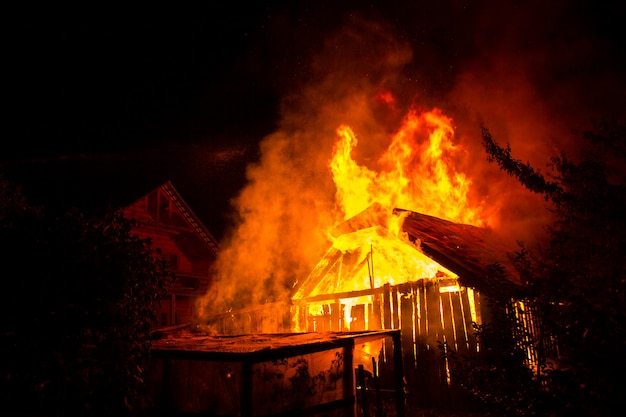 Casa in legno o fienile che brucia sul fuoco durante la notte.