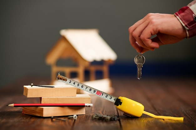 Casa in legno su una superficie di legno da tavole e un mazzo di chiavi con un chip. Concetto - costruzione di case chiavi in mano. Foto di alta qualità