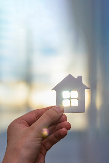 Casa in mano, sotto i raggi del sole. Concetto di protezione della proprietà. Posto per il testo.