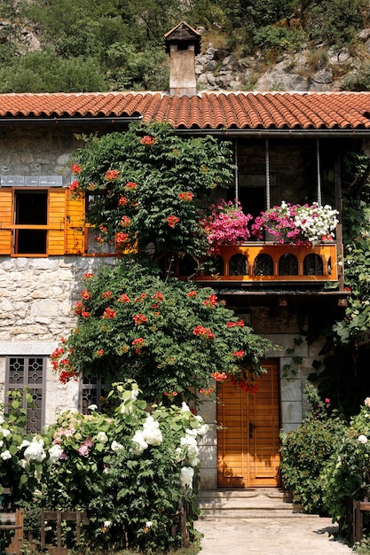 Casa in pietra con tetto in tegole con cespugli fioriti nelle vicinanze. sfondo