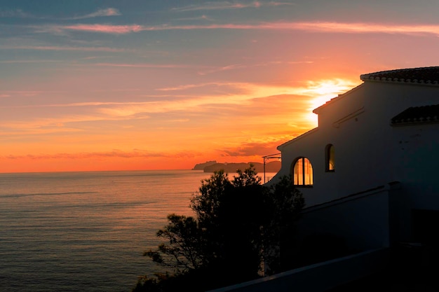 Casa isolata con un tetto di tegole in riva al mare al tramonto javea spane