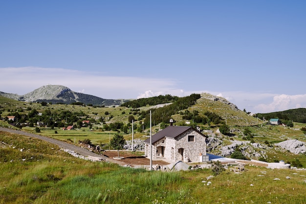 Casa lungo la strada in un villaggio di alta montagna tra alberi erbe e verde