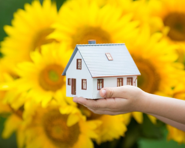 Casa nelle mani dei bambini su sfondo giallo autunnale Concetto di bene immobile