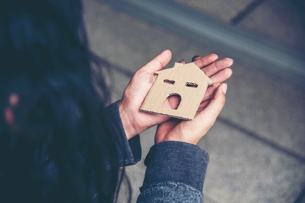 Casa nelle mani di senzatetto povertà mendicante uomo sogno con dolce casa cerca di chiedere lavoro soldi e sperando aiuto in impotente città sporca seduta per strada