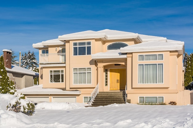 Casa residenziale di lusso con cortile anteriore nella neve in un giorno di inverno soleggiato in Canada