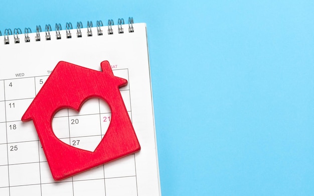 Casa Rossa con un cuore sullo sfondo blu del calendario Modello Copia spazio per il mockup del testo