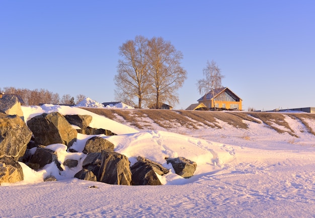 Casa sulla riva dell'Ob Sea Rocks nella neve sulla riva del fiume una casa gialla