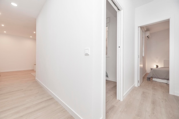 Casa vuota con corridoi con pavimenti in rovere chiaro porte ad altre stanze e pareti dipinte di bianco