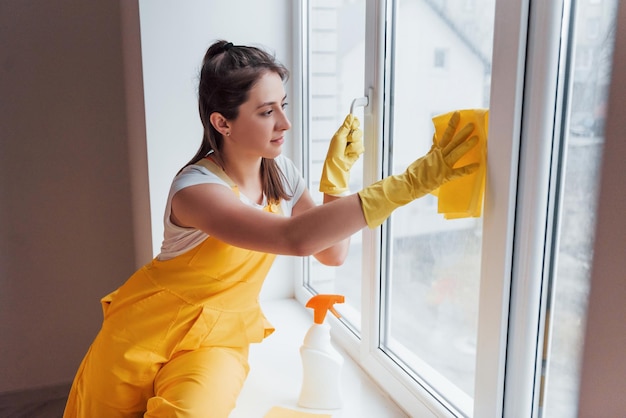 Casalinga in uniforme gialla per la pulizia delle finestre Concezione di ristrutturazione della casa