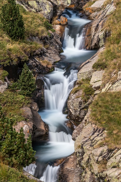 Cascata a cascata di bello velo, rocce muscose in Pirenei in Spagna