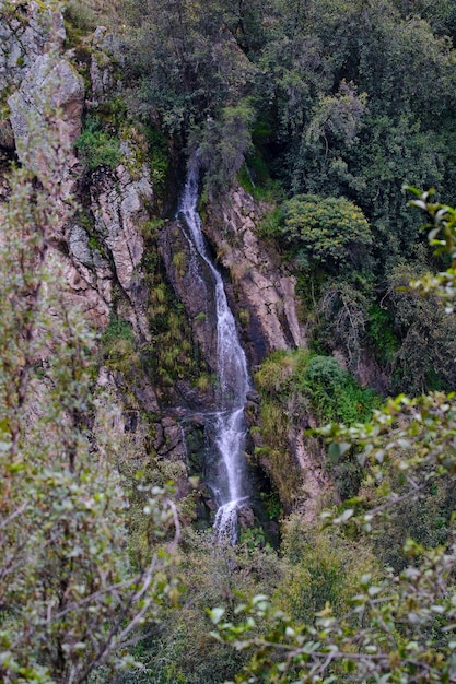 Cascata andina emergente dalle rocce in un paesaggio montano