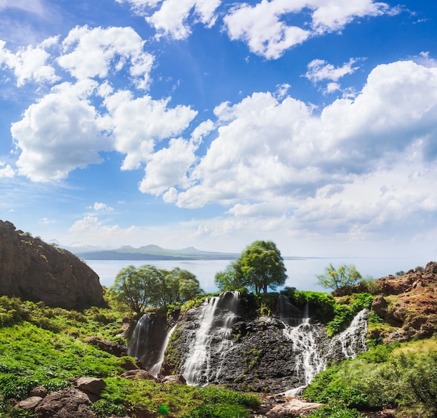 Cascata di montagna con cielo nuvoloso blu