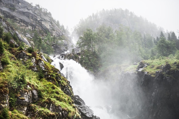 Cascata in montagna in mattinata nebbiosa, Norvegia. Paesaggio estivo