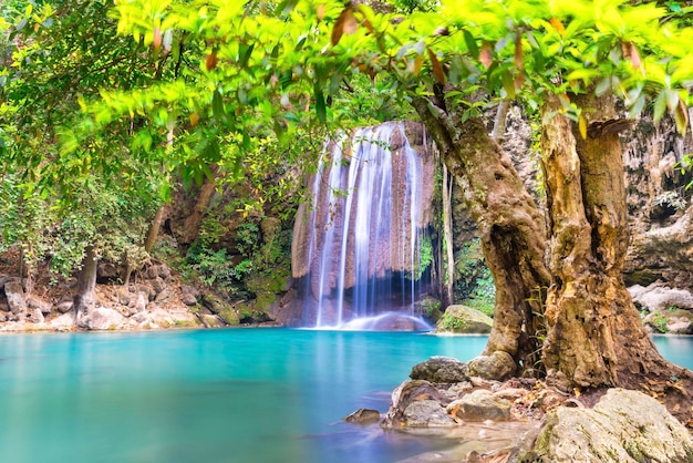 Cascata nella foresta tropicale con albero verde e lago color smeraldo Erawan Thailandia