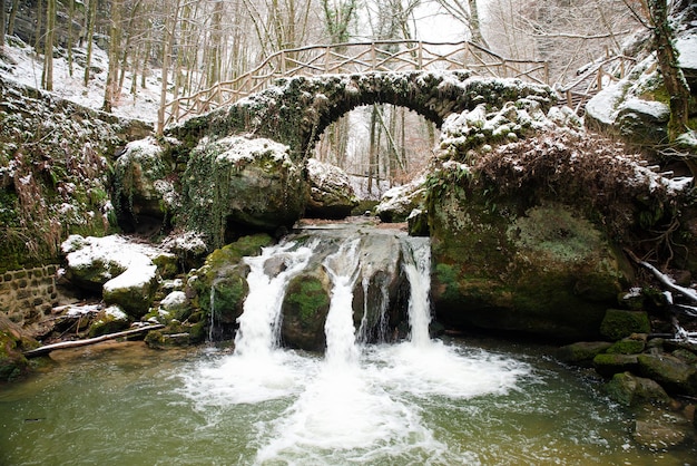 Cascata Scheissentempel, fiume Black Ernz con ponte di pietra coperto di neve, sentiero Mullerthal