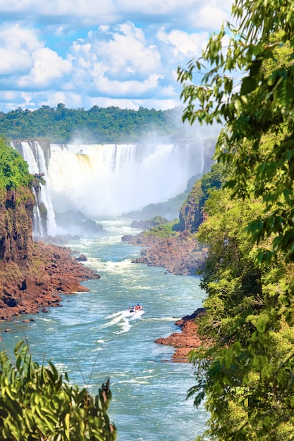 Cascate di Iguazu in Argentina. Barca a motore turistica andando verso la potente cascata d'acqua creando nebbia sul fiume Iguazu. Fogliame lussureggiante della foresta pluviale subtropicale.