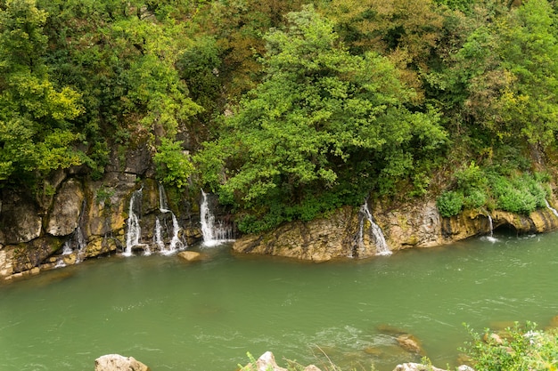 Cascate su un fiume di montagna con acqua verde e coste rocciose