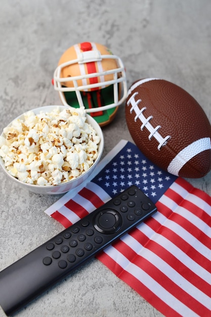 Casco a popcorn a controllo remoto palla da rugby e bandiera americana su sfondo grigio concetto di Superbowl