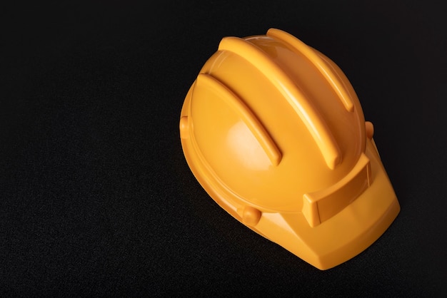 Casco da costruzione giallo su sfondo nero. Copia spazio.