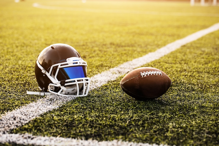 Casco da football americano e palla su erba verde