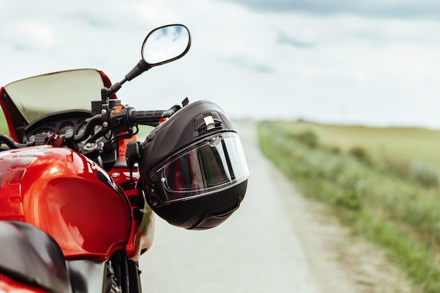 Casco da motociclista nero appeso al manubrio della moto