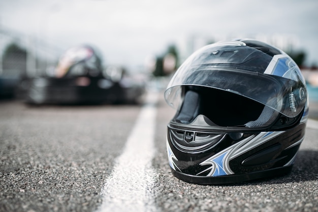 Casco da pilota su asfalto, concetto di sport motoristico kart, pista all'aperto per go kart, gara di kart