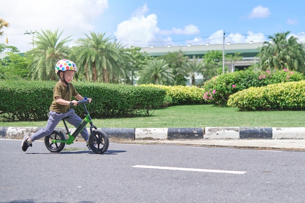 Casco di sicurezza d'uso del bambino sveglio del ragazzino che impara guidare la prima bici dell'equilibrio