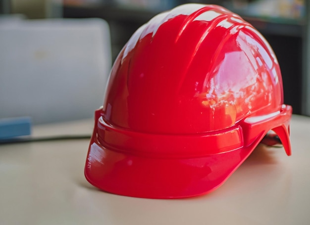 Casco di sicurezza rosso sulla tavola bianca