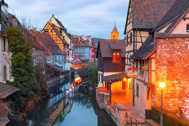 Case a graticcio tradizionali alsaziane, chiesa e fiume Lauch a Petite Venise o piccola Venezia, città vecchia di Colmar, decorate e illuminate a Natale, Alsazia, Francia