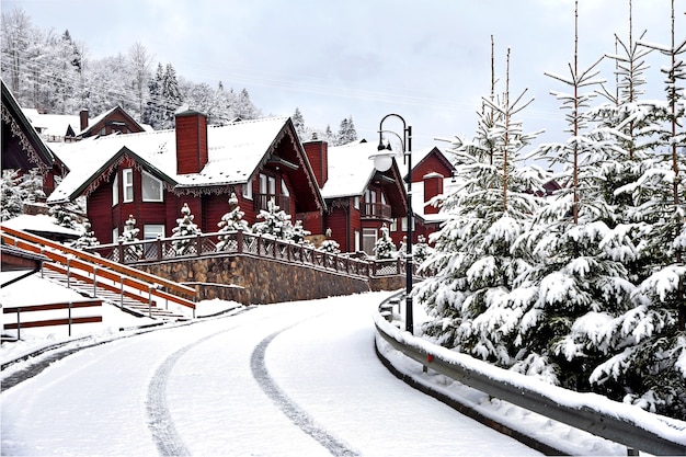 Case di legno casa per le vacanze in località di villeggiatura di montagna ricoperta di neve fresca in inverno. Bella strada invernale dopo la nevicata.