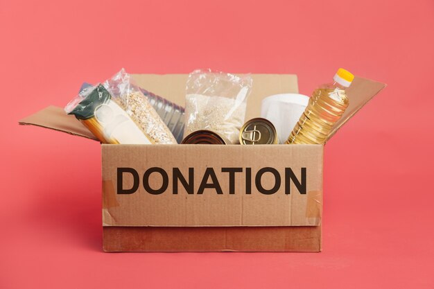 Casella di donazione con cibo isolato su sfondo rosso.