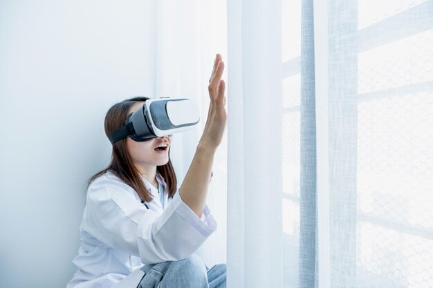Casella VR Una giovane donna asiatica in uniforme da dottore fa un'espressione eccitata mentre impara con la tecnologia VR