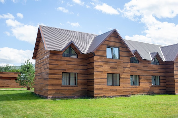 Casetta in legno a due piani con finestre natura con prato verde. Vendita o acquisto di nuove case.