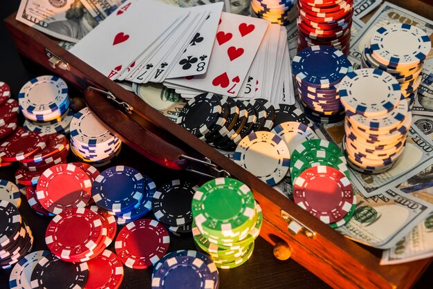 Caso pieno di fiches, dollari e carte da gioco su sfondo nero