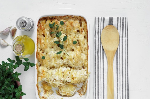 Casseruola Cucina francese Gratin di patate fatte in casa in una padella di ceramica per la cottura Con foglie di origano fresco olio d'oliva aglio Vista dall'alto spazio copia