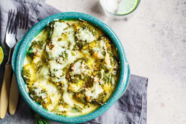 Casseruola dei broccoli con formaggio in piatto blu, fondo grigio. Concetto di cibo vegetariano.