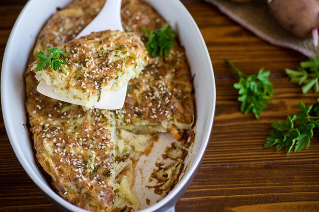 casseruola di patate con cavolo e spezie in forma ceramica su un tavolo di legno