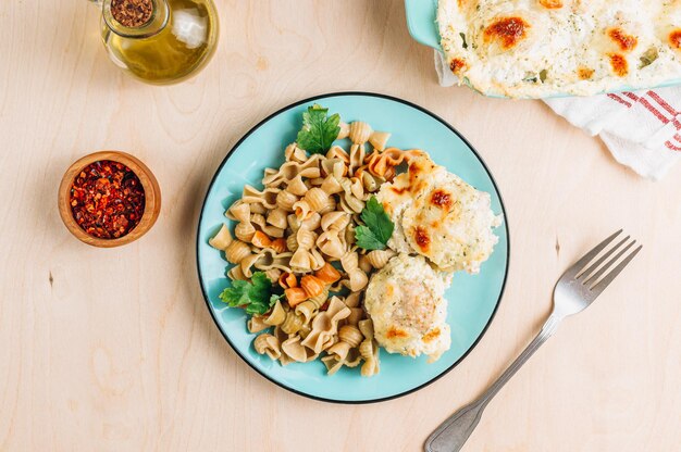 Casseruola di polpette di formaggio al forno nella pirofila Piatto blu con pasta di pomodoro e spinaci e