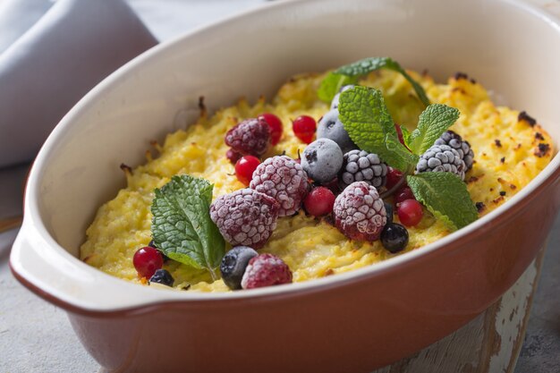 Casseruola di ricotta al forno con con frutti di bosco freschi sul tavolo della cucina.