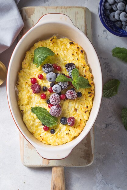 Casseruola di ricotta al forno con con frutti di bosco freschi sul tavolo della cucina.