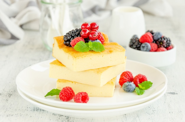 Casseruola di ricotta fatta in casa con frutti di bosco freschi e menta in cima su un piatto bianco. Colazione salutare. Orizzontale, copia spazio.